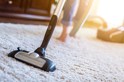 vacuuming white carpet with vacuum cleaner