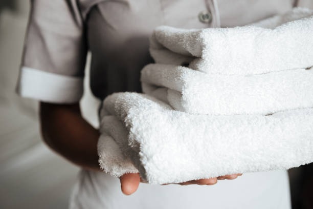 housemaid in proper uniform carrying white towels